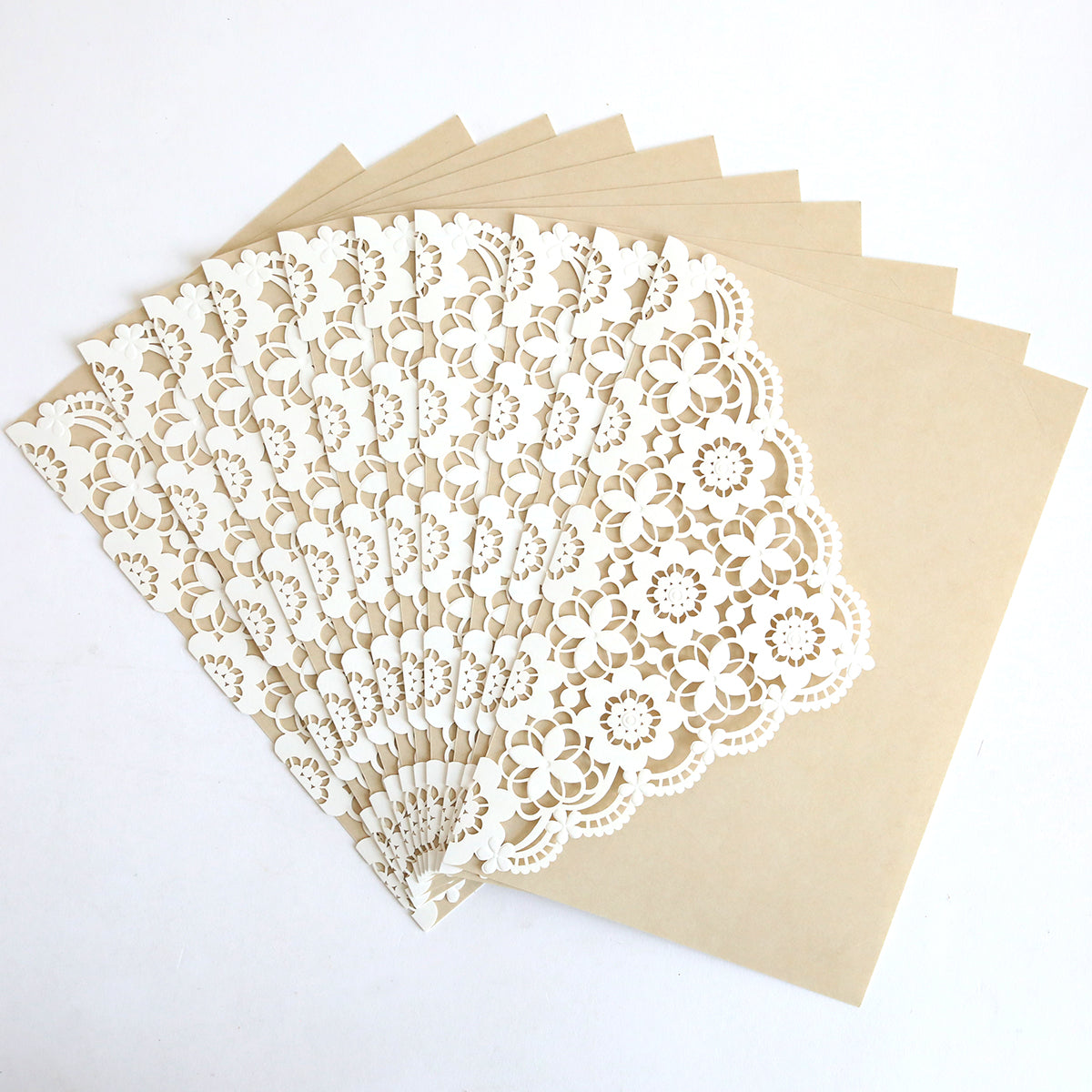 The Lace Laser Cut Invitation 10 pack features beige envelopes with white, lace-patterned overlays—ideal for elegant wedding invitation wraps or sophisticated lace lasercut invitations.