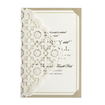A white and gold wedding invitation with a laser cut design.