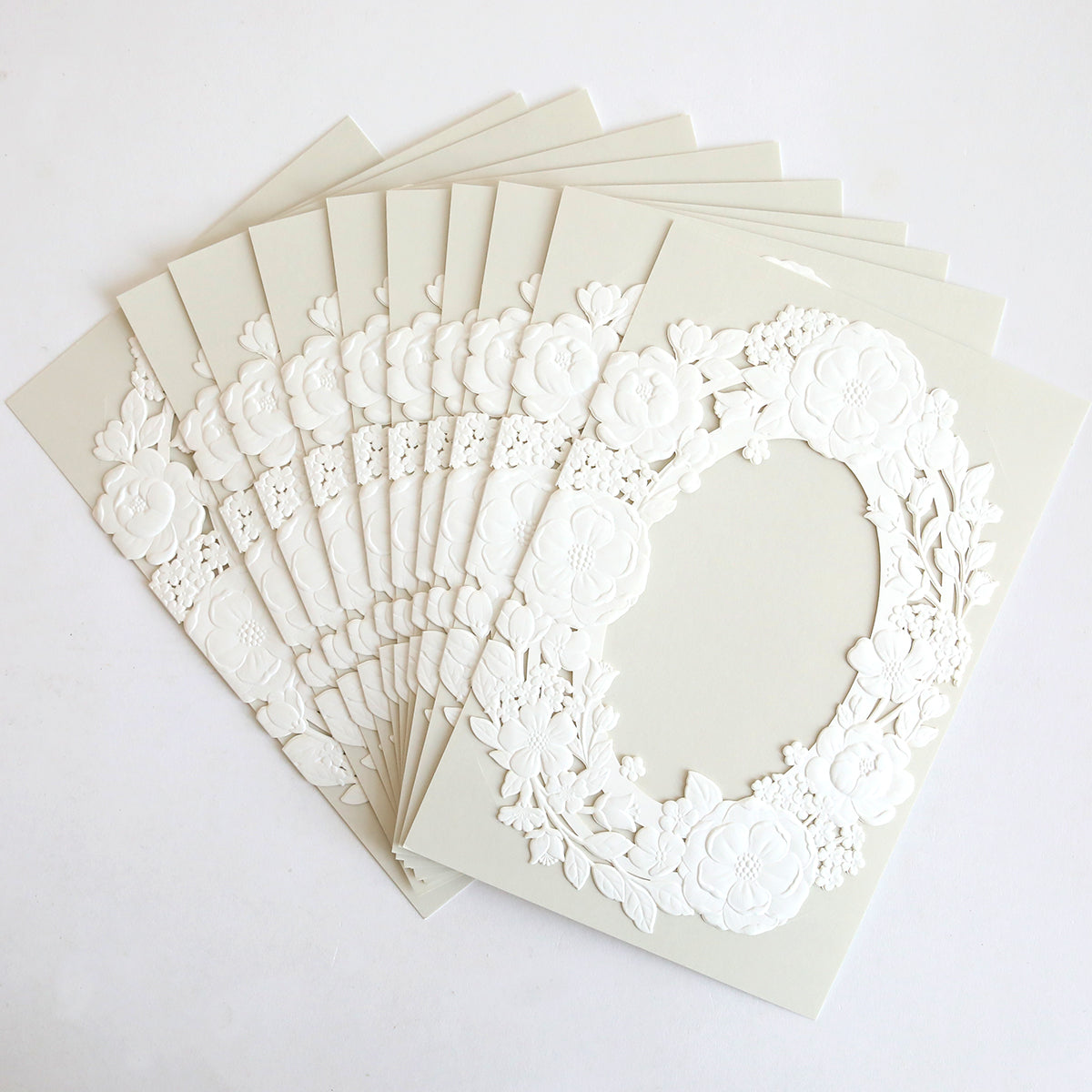 Ten Floral Wreath Laser Cut Invitations (10 pack) are elegantly fanned out, each featuring a delicate floral wreath design—ideal for stylish wedding invitation wraps.