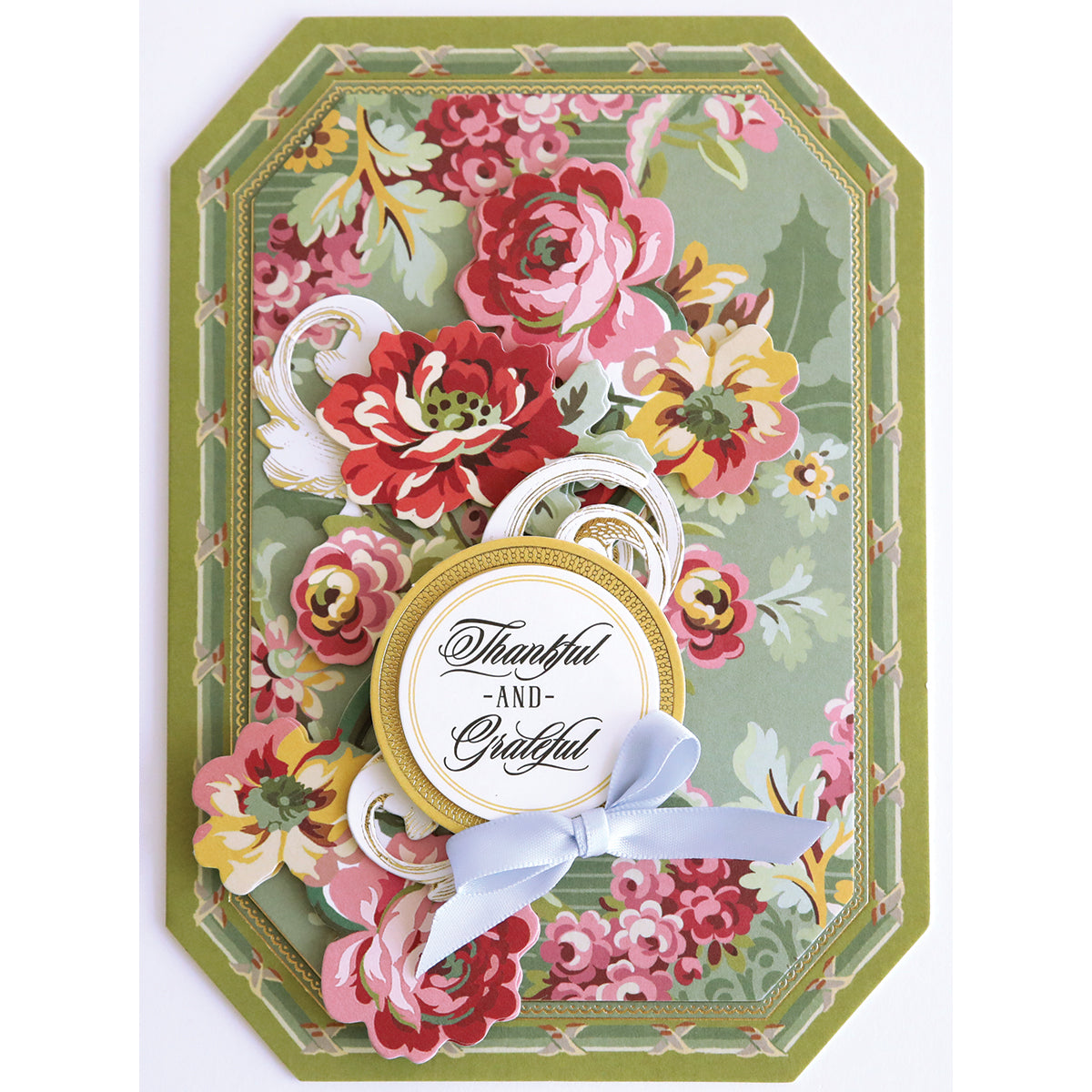 A handmade Simply Thank You Card Making Kit featuring a green floral background, layered paper flowers, a light blue ribbon, and a center medallion reading “Thankful -AND- Grateful.”