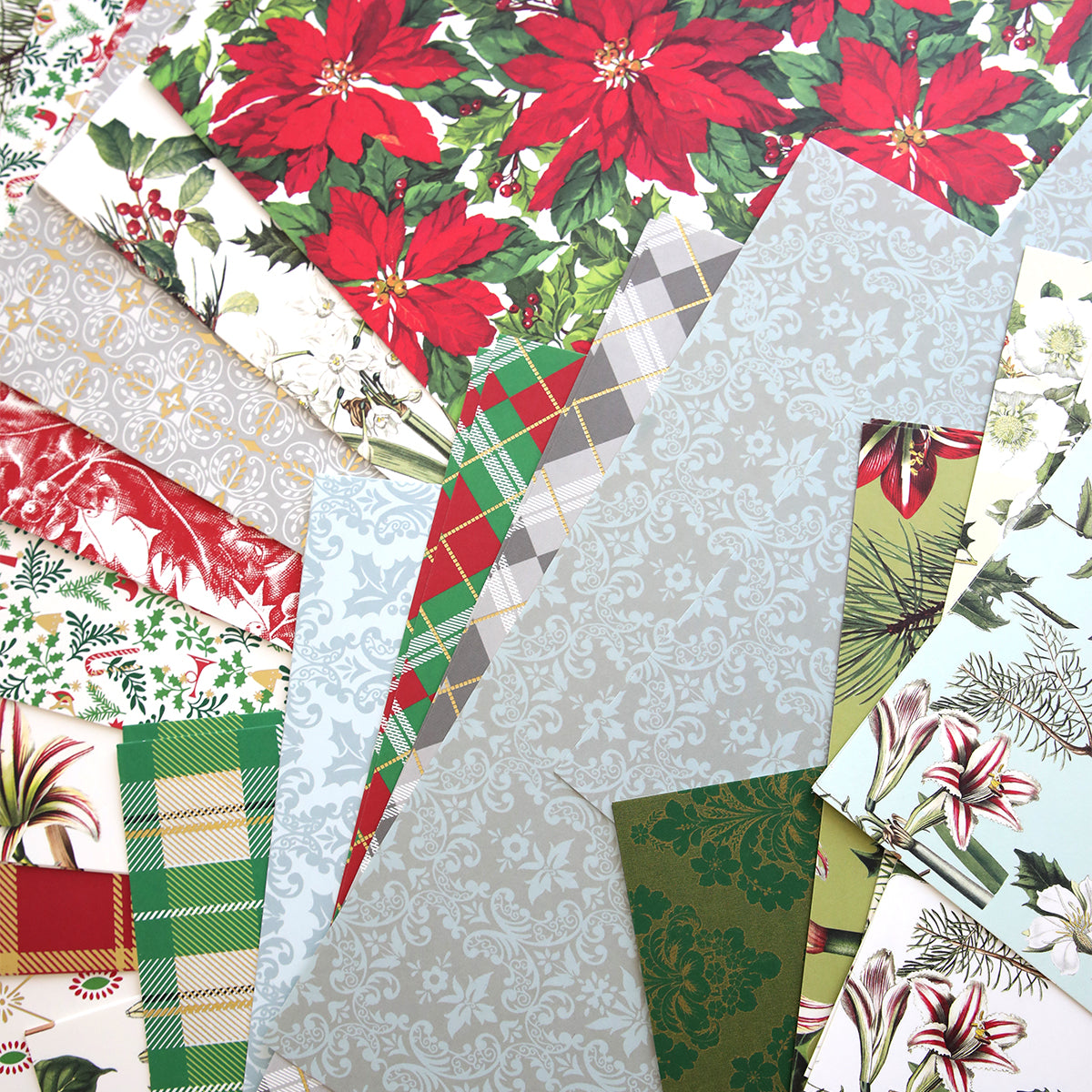 A variety of holiday-themed wrapping papers, including poinsettias, plaid, and floral designs, arranged on a flat surface. Ideal for Christmas cardstock projects using 12x12 sheets from the Christmas Cardstock Collection.