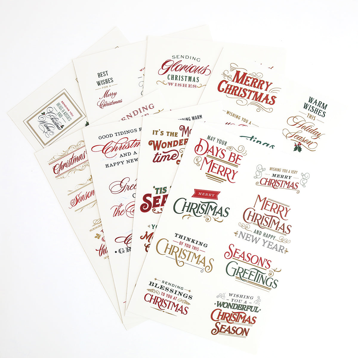 A collection of high quality Christmas Greetings Rub On Transfers and various decorative holiday-themed greeting cards are laid out in a fan-like arrangement on a flat surface.