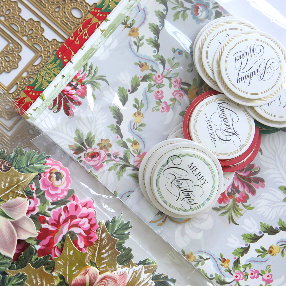 The Eyelet Elegance Dies and Materials set features Christmas-themed crafting essentials, including floral paper and gold die-cut designs, all elegantly arranged with satin ribbons and round festive greeting labels, offering a delightful assortment for your holiday projects.