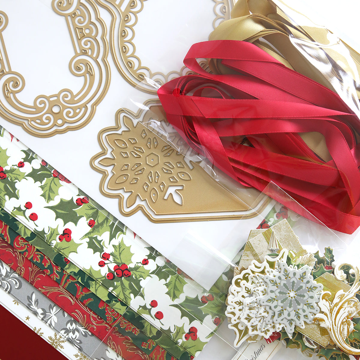 Product Name: Festive Tags Dies and Materials  
Description: A collection of holiday-themed crafting materials featuring red and gold satin ribbons, decorative paper adorned with holly designs, intricate cutouts of gold and white snowflakes, festive tags perfect for personalized messages, and durable cardstock for crafting unique seasonal cards.