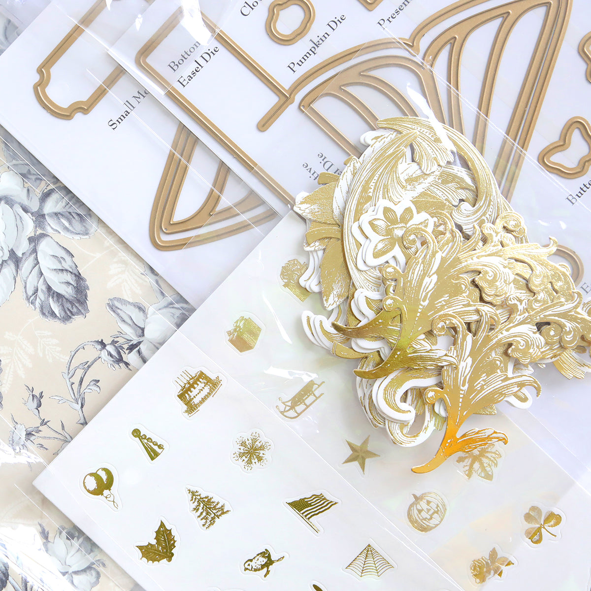 A selection of Creative Calendar Stamps, Dies and Materials, incorporating gold embellishments, stencil shapes, patterned paper, and clear stamps for enhanced detail.