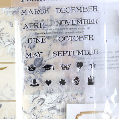 The Creative Calendar Stamps, Dies and Materials set features clear stamps with the months and icons such as a pumpkin, graduation cap, and butterfly on a floral backdrop. It's ideal for use with Creative Calendar Dies or cardstock projects and also includes symbols like a balloon, top hat, dollar sign, heart, snowflake, and gift box.