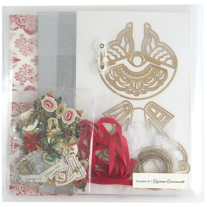 The Origami Ornaments Dies and Materials collection includes a variety of crafting materials such as decorative paper, silver glitter, red ribbons, cardstock cutout shapes, and 3D embellishments, all neatly arranged in a clear organizer.