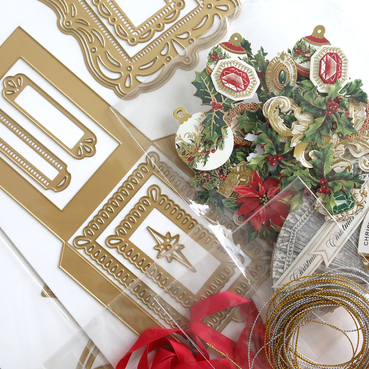 The Origami Ornaments Dies and Materials, featuring gold embossed frames, intricate origami ornaments with holly designs, red ribbon, and gold string, are artfully arranged on a white surface.