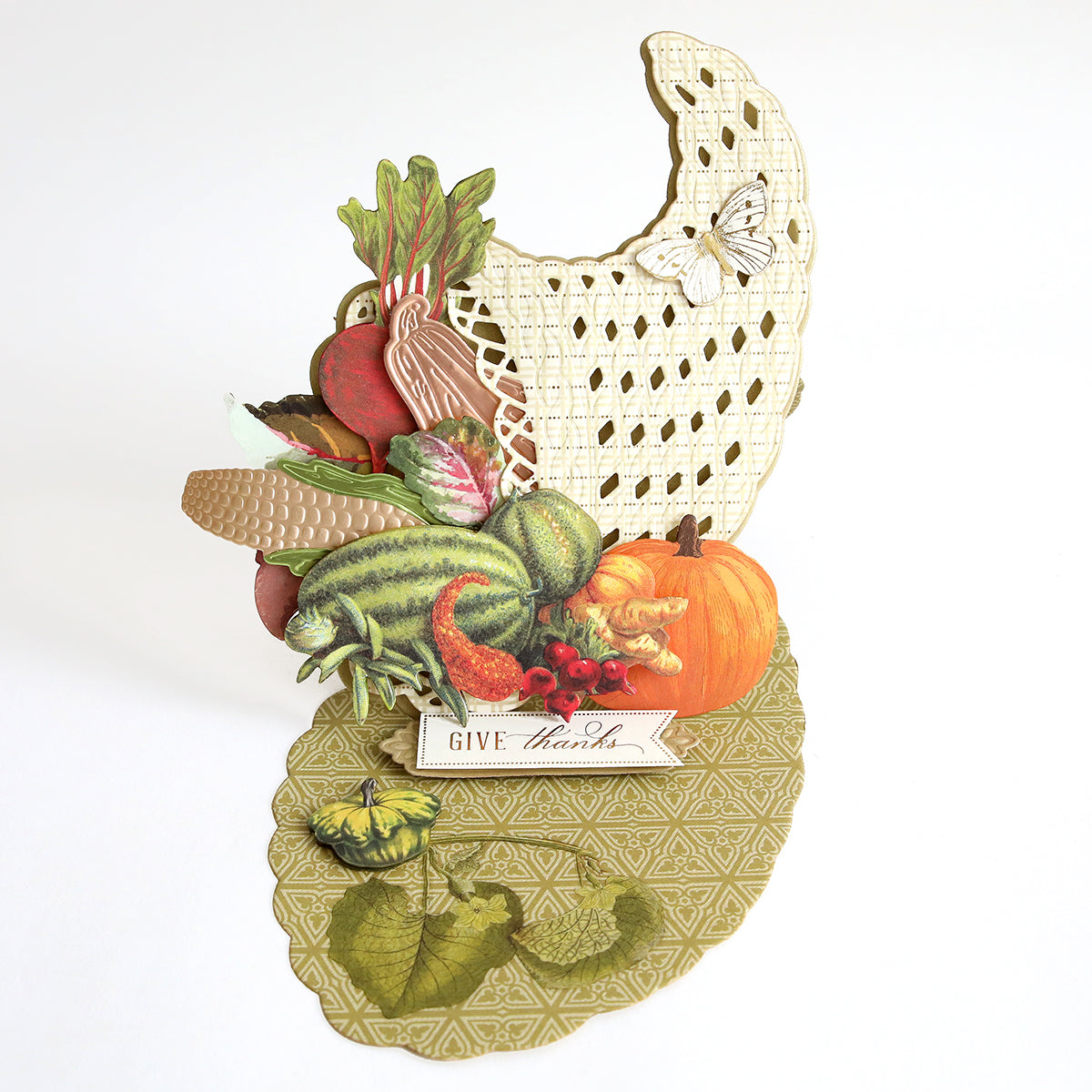 Create a stunning Thanksgiving card or festive table décor with the Cornucopia Easel Card Dies—featuring detailed vegetables, fruits, and a pumpkin on an intricately patterned base, complete with a “Give thanks” sign and butterfly accents on a cut-out background.