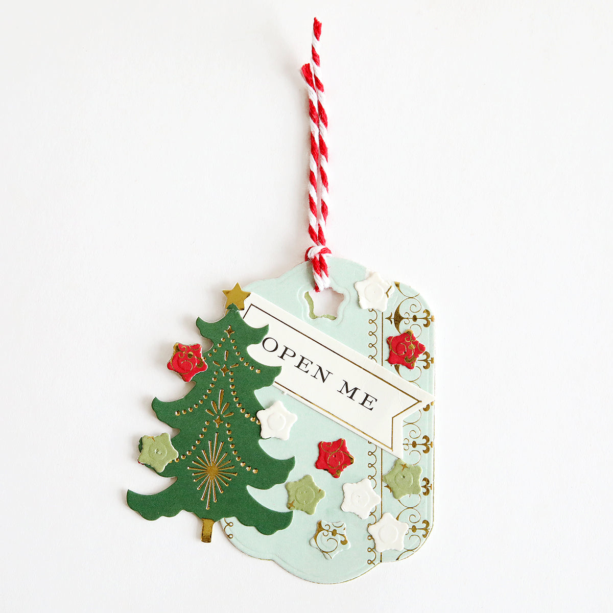 Creative Tag Dies create decorative Christmas gift tags with a green tree, red and white flowers, gold accents, a red-white string, and "OPEN ME"—perfect for adding a creative touch to your holiday gifts.