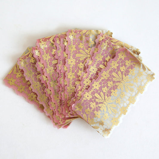 Ten Gold Foil Vellum Lace Band wedding invitations feature pink and white rectangular cards with intricate gold lace patterns and elegant vellum bands, beautifully displayed on a white surface.
