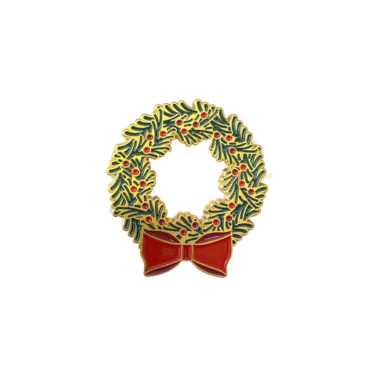 The Members Only December Pin is a decorative enamel pin shaped like a green holiday wreath with red berries and a large red bow, part of our 2025 Exclusive Pins collection.