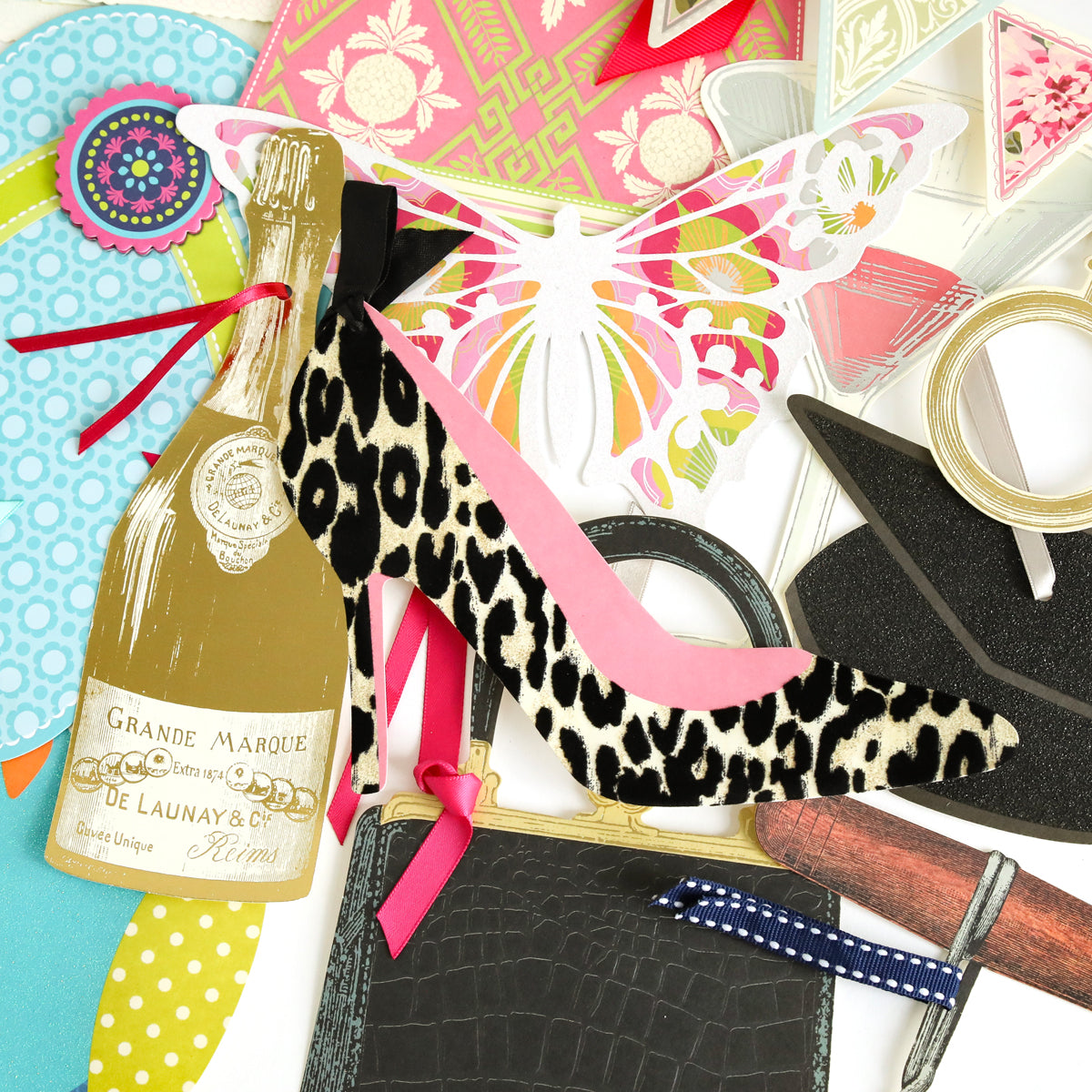 Featuring the All Occasion Extreme Diecut Assortment—a vibrant collage of diecut images such as a champagne bottle, high heel shoe, butterfly, purse, hat, flowers, and ribbon—artfully arranged on a white background. Perfect for embellishing scrapbook pages or handmade cards.