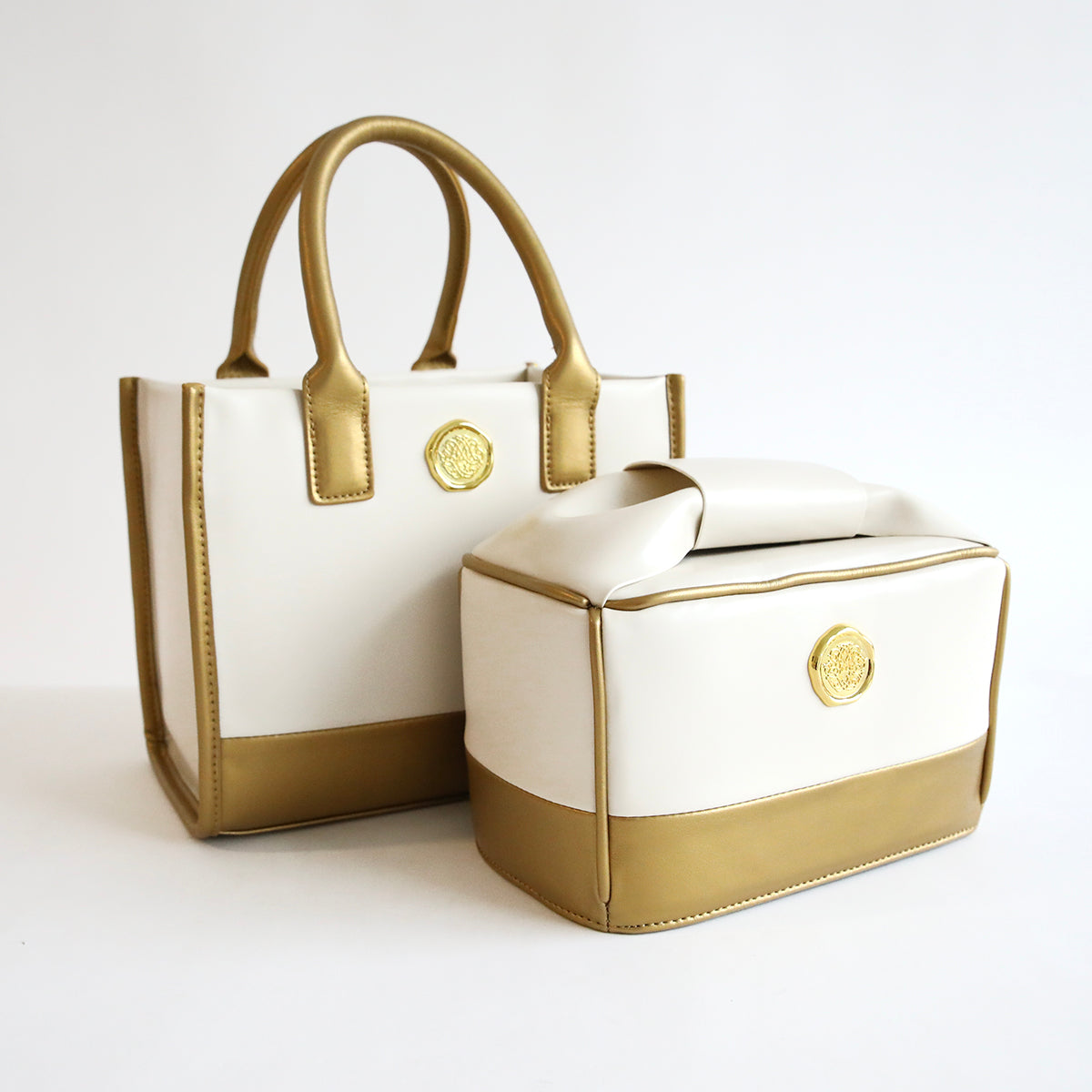 Two white Empress Mini Tote and Dust Cover handbags on a white surface.