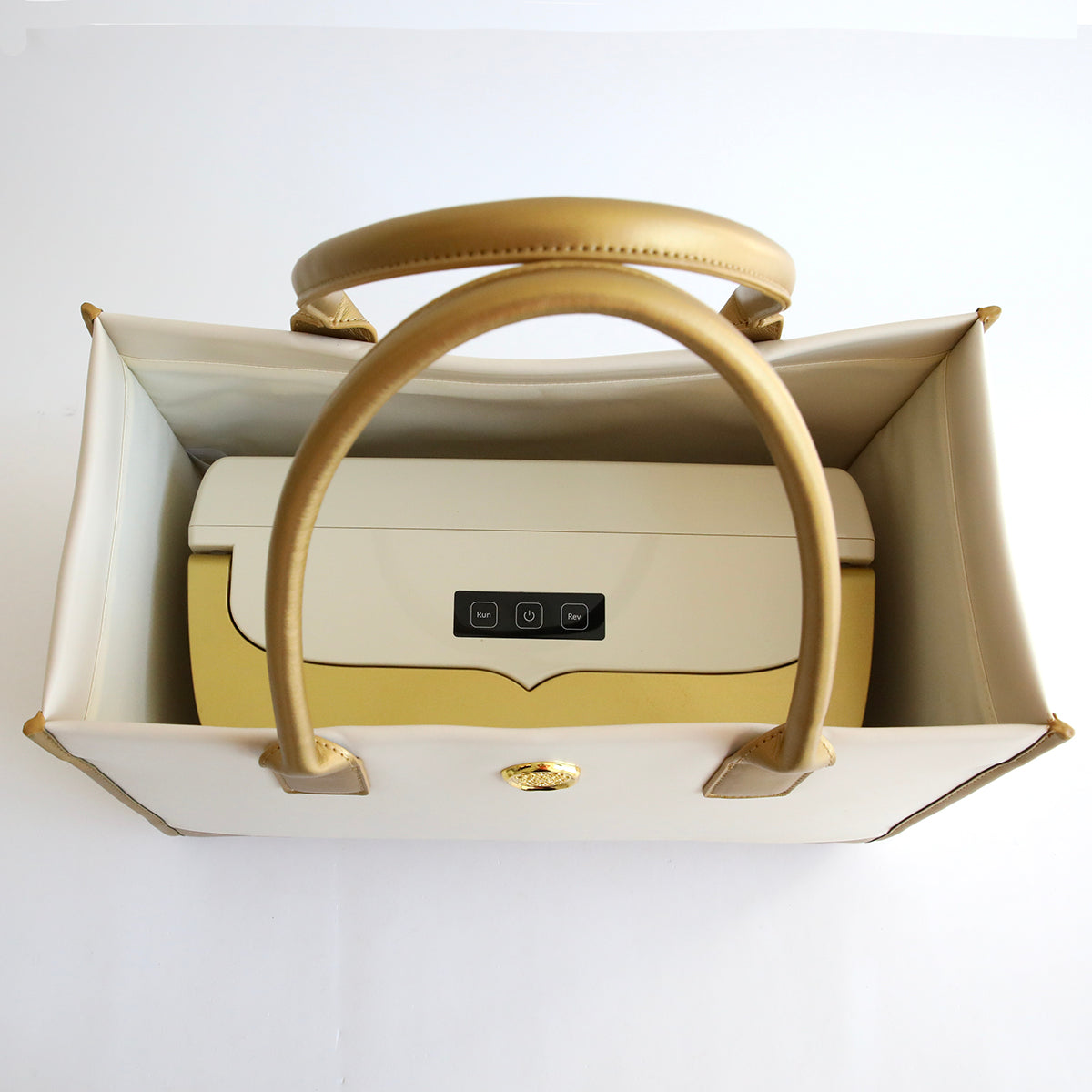 An elegant Empress Machine Tote Bag in an ivory palette with a darker tan handle and accents, placed inside its open box with the interior lining and brand logo visible.