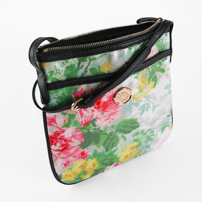 The Virginia Crossbody is a floral-patterned laminated cotton purse featuring a gold emblem, black trim, and a zipper closure, photographed on a white background—perfect as a stylish crossbody bag and thoughtful gift for women.