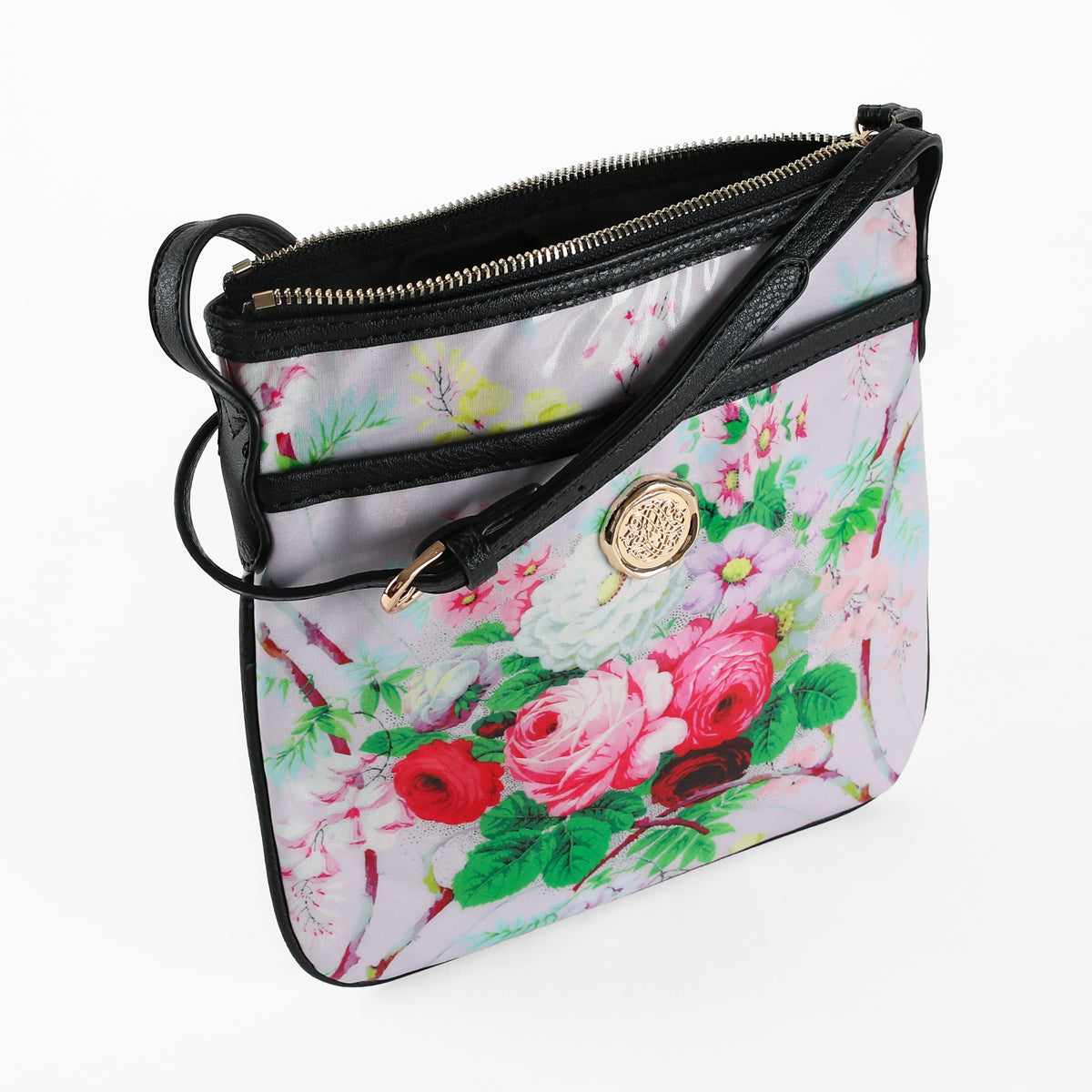 The Lillian Crossbody, crafted from laminated cotton with a floral pattern, features black trim, a gold medallion detail, and a zippered top—shown against a white background.