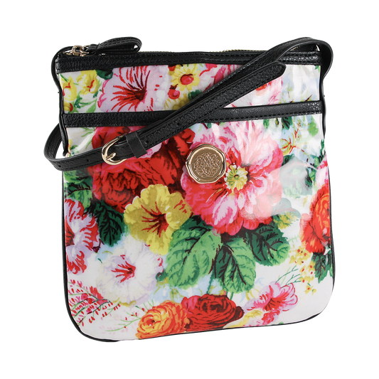 The Annalise Crossbody Bag is displayed against a white background, featuring a floral design with a gold emblem, black edging, and a coordinating black strap. Crafted from laminated cotton, this chic shoulder bag for women seamlessly combines elegance and practicality.