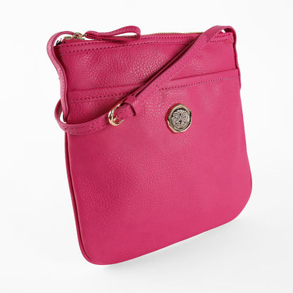 The Raspberry Pink Crossbody Bag showcases vibrant faux leather with a gold emblem and zipper closure, set against a plain white background.