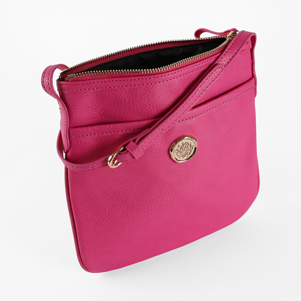 The Raspberry Pink Crossbody Bag features a vibrant raspberry pink hue, crafted from luxe faux leather. It is designed with a gold circular emblem, front pocket, and adjustable strap, and is displayed against a white background.