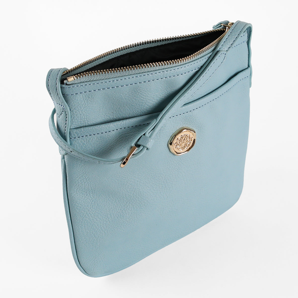 Introducing the Beach Glass Blue Crossbody Bag: a slim, minimalist design crafted in light blue faux leather, featuring an adjustable strap, a convenient front pocket, a top zipper closure, and embellished with a gold circular emblem.