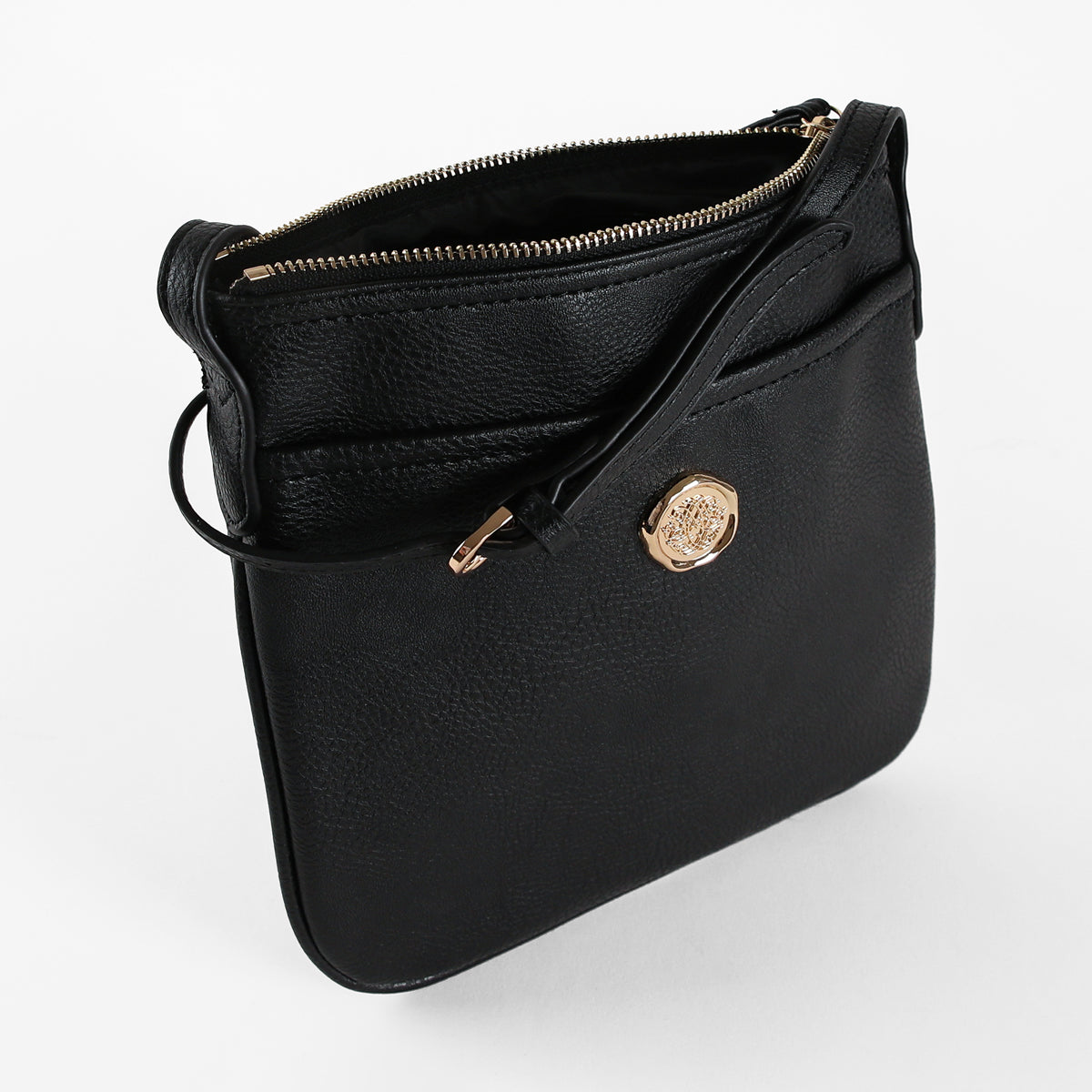The Onyx Black Crossbody Bag is a women’s shoulder bag crafted from black faux leather, featuring a gold zipper and a circular gold emblem on the front, displayed against a white background.