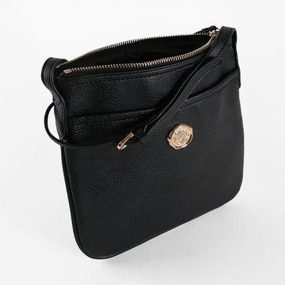 The Onyx Black Crossbody Bag is a women’s shoulder bag crafted from black faux leather, featuring a gold zipper and a circular gold emblem on the front, displayed against a white background.