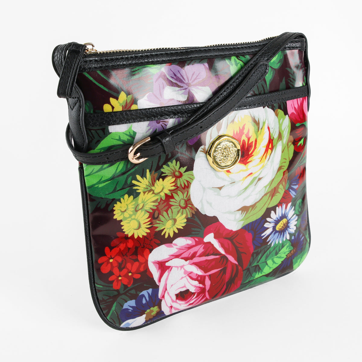 Introducing the Astrid Crossbody—a stylish hands-free bag crafted from durable laminated cotton, combining fashion and practicality for everyday use. This crossbody features a black strap, a gold decorative button, and showcases bold, colorful floral designs set against a dark background.
