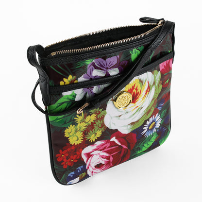 Sure! Here’s a rewritten version using the product name: The Astrid Crossbody is a stylish floral bag crafted from laminated cotton, featuring a gold zipper, chic black accents, and a striking gold emblem on the front pocket for hands-free convenience.