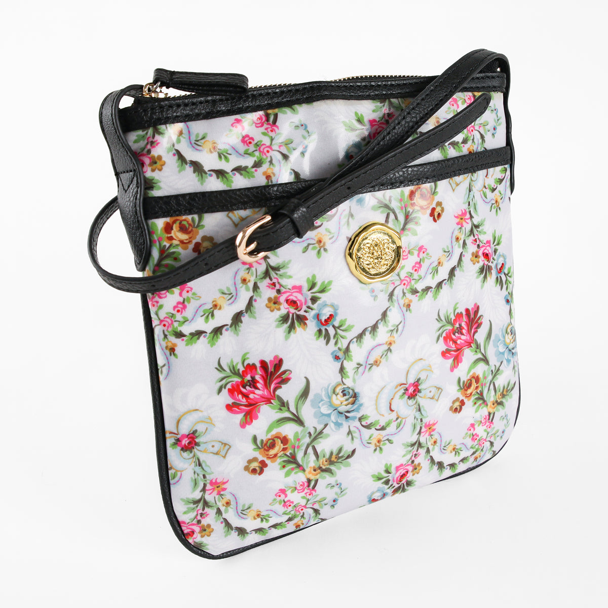 Introducing the Phoebe Crossbody—a floral-patterned crossbody bag featuring a black strap and a gold medallion accent on the front, crafted from durable laminated cotton and displayed on a white background. The Phoebe Crossbody is an ideal gift for women who value both style and practicality.