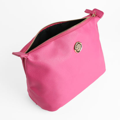 Introducing the Raspberry Pink Large Cosmetic Bag—a spacious makeup bag made from raspberry pink faux leather, featuring a zippered closure and adorned with a gold circular emblem. Displayed against a white background, it serves as a stylish travel toiletry bag.