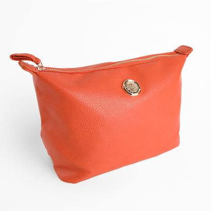The Tangerine Orange Large Cosmetic Bag is crafted from faux leather, features a gold emblem on the front, and is photographed against a plain white background.