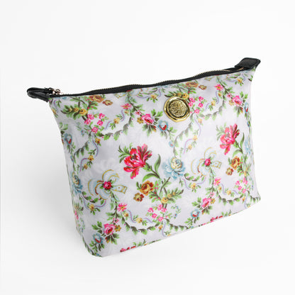 The Phoebe Large Cosmetic Bag, crafted from laminated cotton in a floral pattern and adorned with a gold medallion detail on the front, is displayed against a white background. Combining style with practical durability, this spacious bag is perfect as a floral travel makeup pouch.