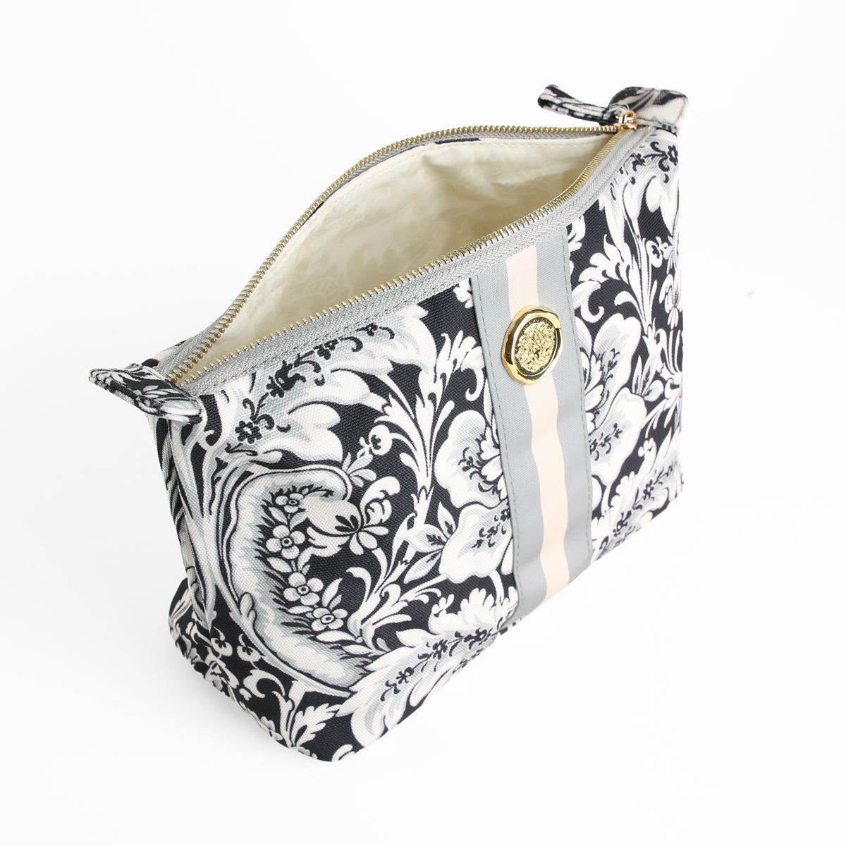 The Damask Noire Large Cosmetic Bag features a classic black and white floral damask pattern with a vertical stripe and gold button detail. This spacious zippered travel cosmetic bag is shown open, revealing its light-colored interior.