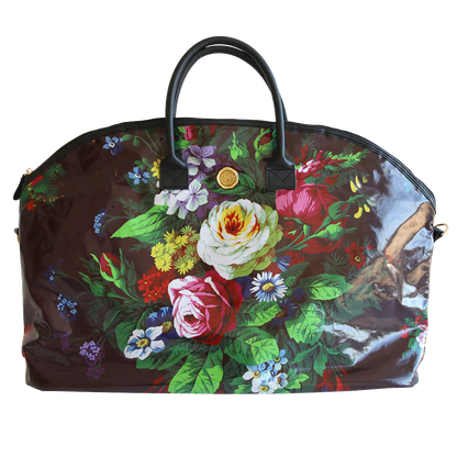 A floral-patterned, dome-shaped Astrid Duffle Bag with vibrant multicolored flowers and green leaves on a translucent brown background, featuring black handles and a gold clasp.