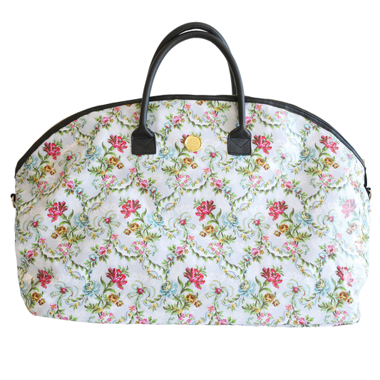 Phoebe Duffle Bag in floral-patterned, dome-shaped handbag with dark handles and a metallic clasp, featuring a nylon interior, isolated on a white background.