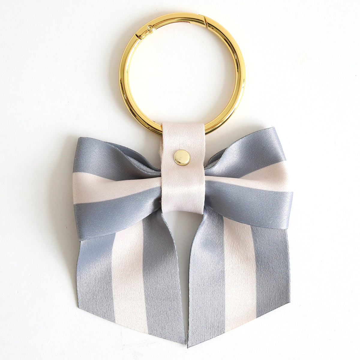The Gray Stripe Bag Charm features a stylish keyring with a decorative gray and white striped ribbon bow, making it a chic accessory for your bag.