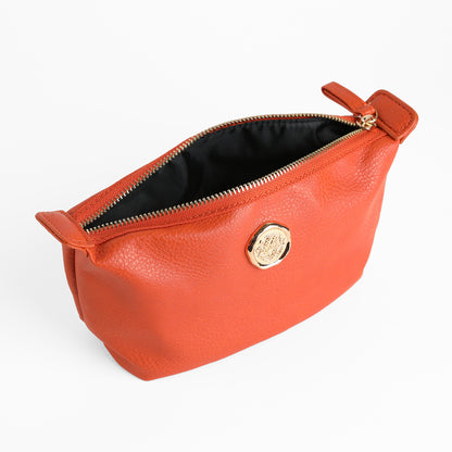 Tangerine Orange Small Cosmetic Bag featuring a gold circular emblem on the front and a black fabric lining—partially open, it’s perfect as a compact travel makeup pouch.