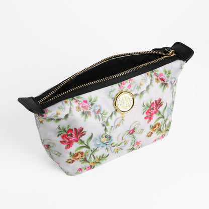 Phoebe Small Cosmetic Bag with elegant floral pattern, featuring a gold circular emblem, black zipper and trim, displayed on a white background. Made from laminated cotton for enhanced beauty and durability, this cosmetic pouch is perfect for storing your makeup essentials.