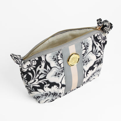 Damask Noire Small Cosmetic Bag features a black and white floral damask pattern, a gold button, and gray and beige vertical stripes on the front, all showcased against a white background. This elegant small pouch doubles as a chic travel makeup bag, making it an ideal gift for any occasion.