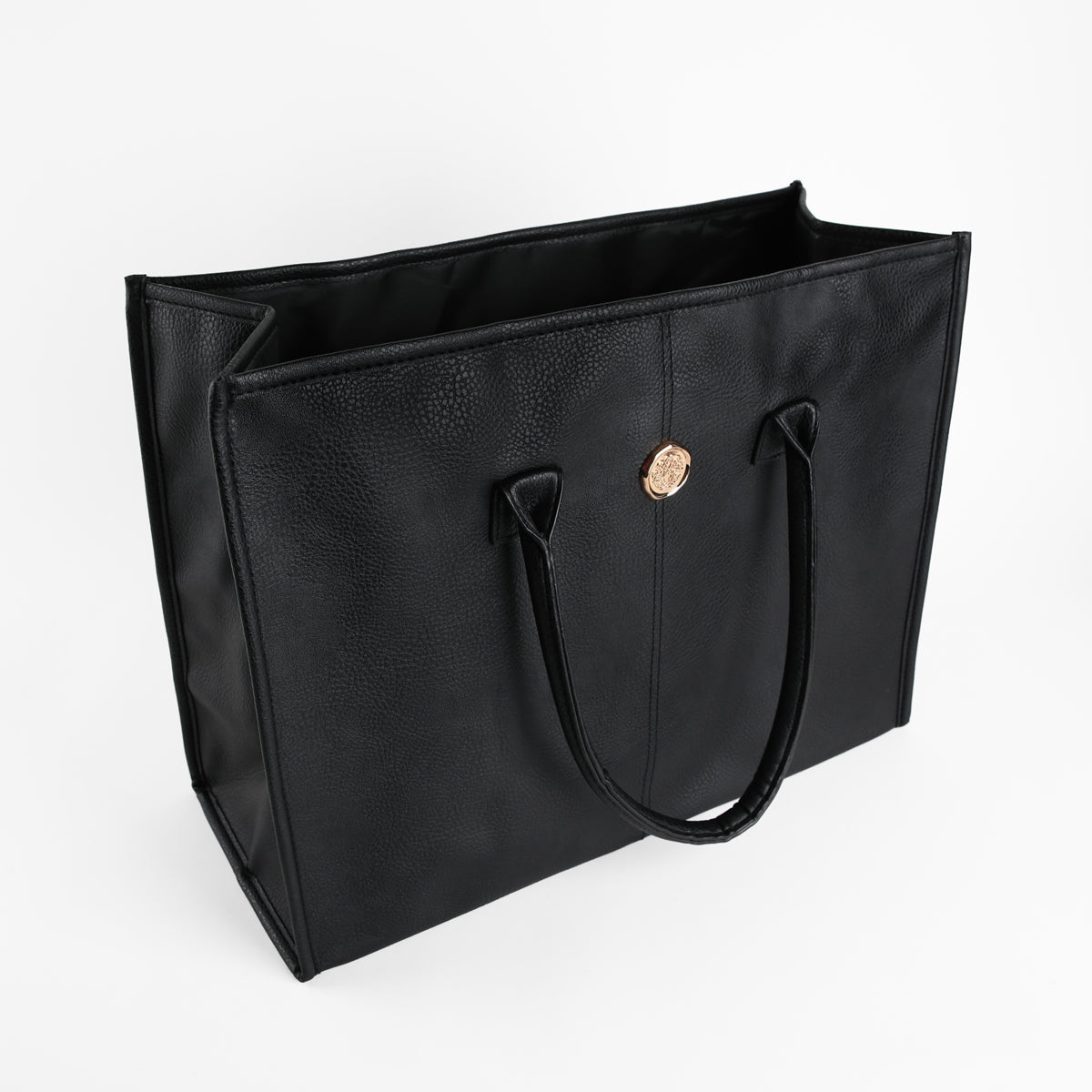 Introducing the Onyx Black Tote Bag: a spacious faux leather tote for women, featuring two handles and a striking gold circular emblem on the front, elegantly photographed against a white background.