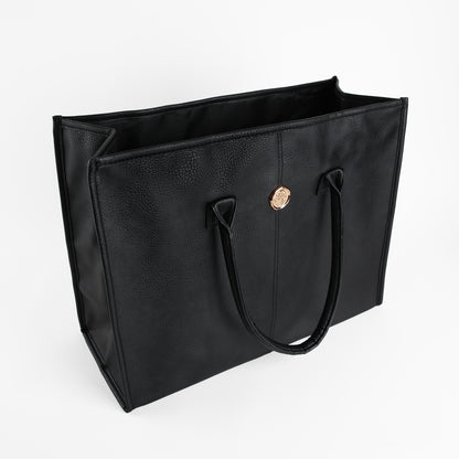 Introducing the Onyx Black Tote Bag: a spacious faux leather tote for women, featuring two handles and a striking gold circular emblem on the front, elegantly photographed against a white background.