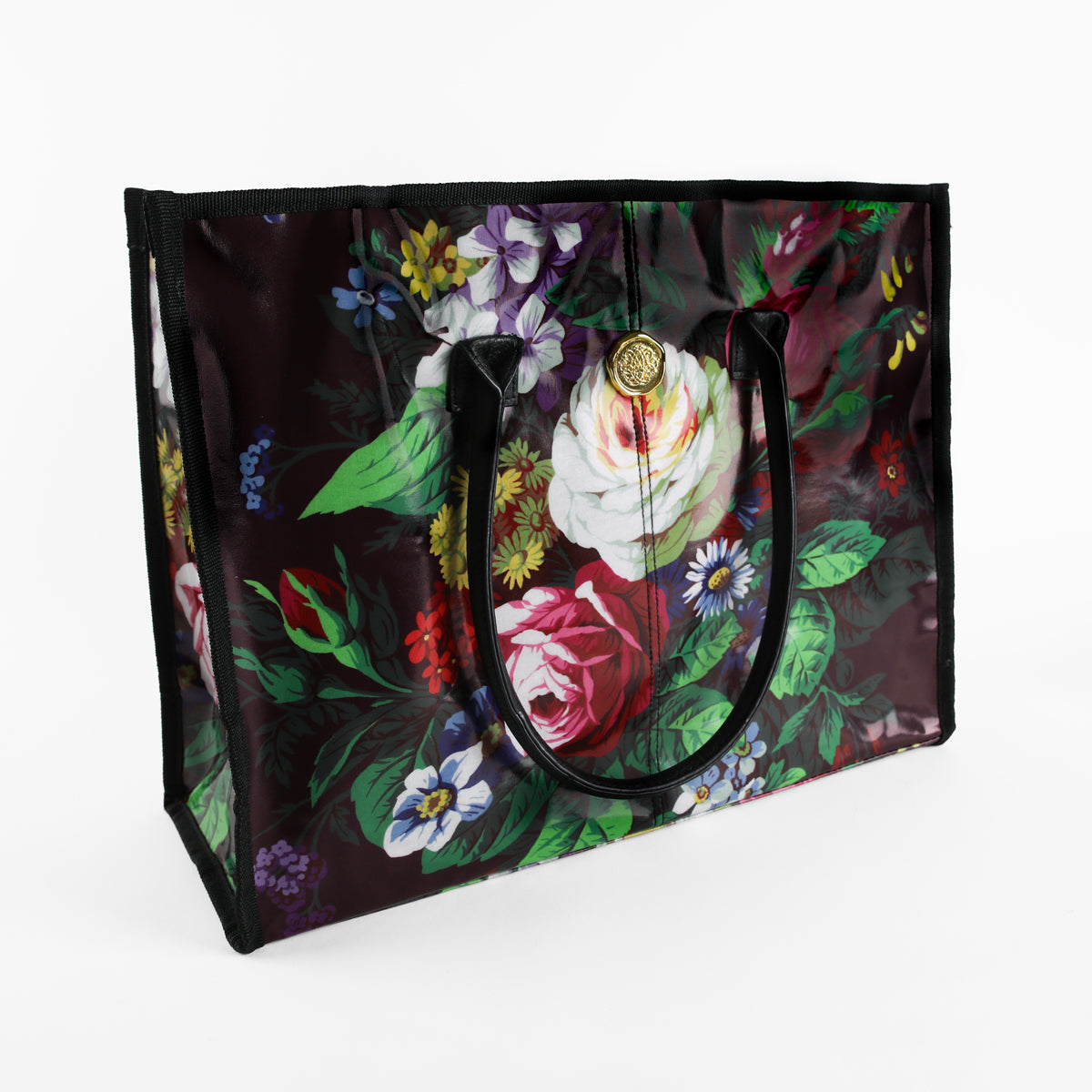 Introducing the Astrid Tote Bag: a large rectangular tote for women featuring sturdy black handles, a glossy laminated cotton finish, and a vibrant floral design with roses and assorted flowers set against a dark background. Stylish yet durable, this floral tote is ideal for everyday use.