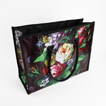 The Astrid Tote Bag is a large, reusable tote for women featuring sturdy black handles and a vibrant floral pattern on a dark background. Crafted from easy-to-clean laminated cotton, this stylish tote is perfect for shopping or everyday use. Shown here on a white surface.