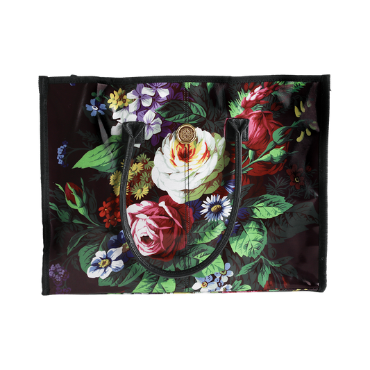 The Astrid Tote Bag is a spacious black laminated cotton tote for women, showcasing a vibrant floral pattern with roses, daisies, and green leaves. Featuring two sturdy black handles, this stylish floral tote bag is perfect for everyday use.