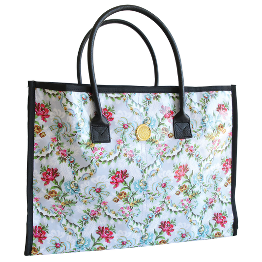 Phoebe Tote Bag with black handles and a circular gold emblem on the front, isolated on a white background.