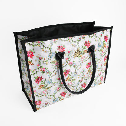 Introducing the Phoebe Tote Bag—a large tote bag with black handles and trim, showcasing a beautiful floral pattern with pink and green accents on a white background. This stylish shoulder bag offers ample space, making it the perfect everyday accessory for women seeking a chic and practical large tote.