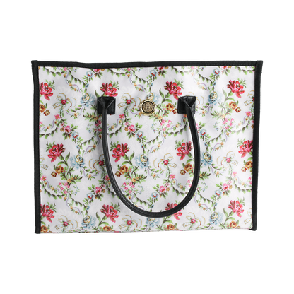 Introducing the Phoebe Tote Bag—a standout large tote for women featuring a vibrant, colorful floral pattern. Designed with black handles, sleek black trim, and a gold circular emblem near the top center, this stylish everyday shoulder bag effortlessly combines function and flair.