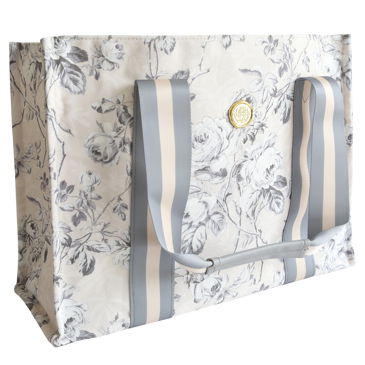 The Faded Rose Tote Bag features a durable gray and white floral print, wide striped handles, and a gold emblem on the front—perfect for everyday use.