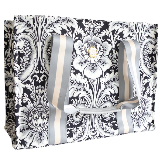 The Damask Noire Tote Bag features a black and white floral design, two wide gray and white striped handles, and is crafted from durable cotton for versatile everyday use.